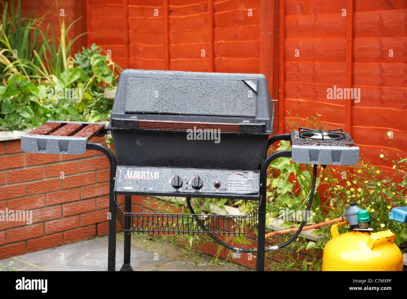 wet gas bbq soaked in heavy rainfall in a garden in the uk Stock Photo