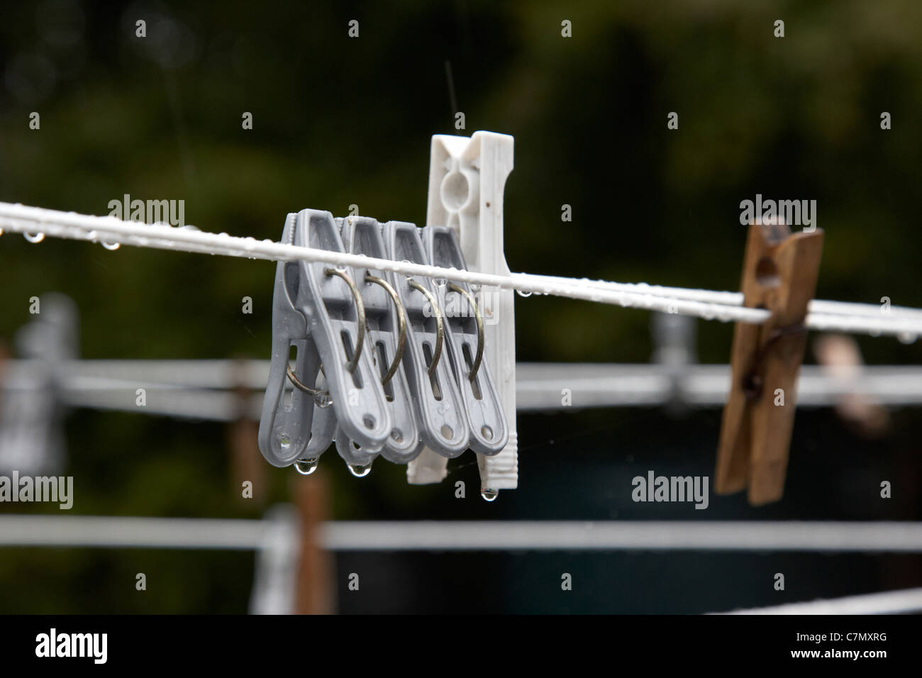 used plastic clothes pegs hanging on a wet washing line in heavy rain Stock Photo