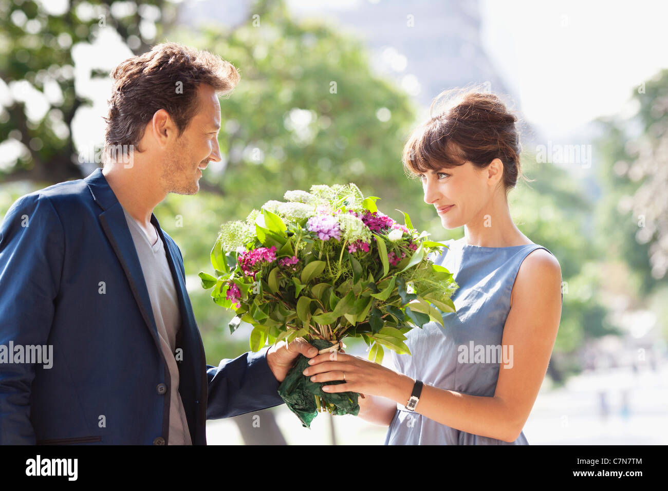 Man giving a bouquet of flowers to a woman with the Eiffel Tower in the