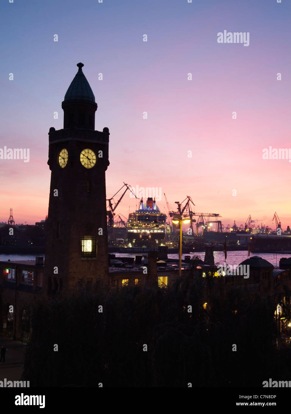Silhouette of the Landungsbruecken with passenger cruise ship Queen Mary 2 in the shipyards, Hamburg, Germany Stock Photo