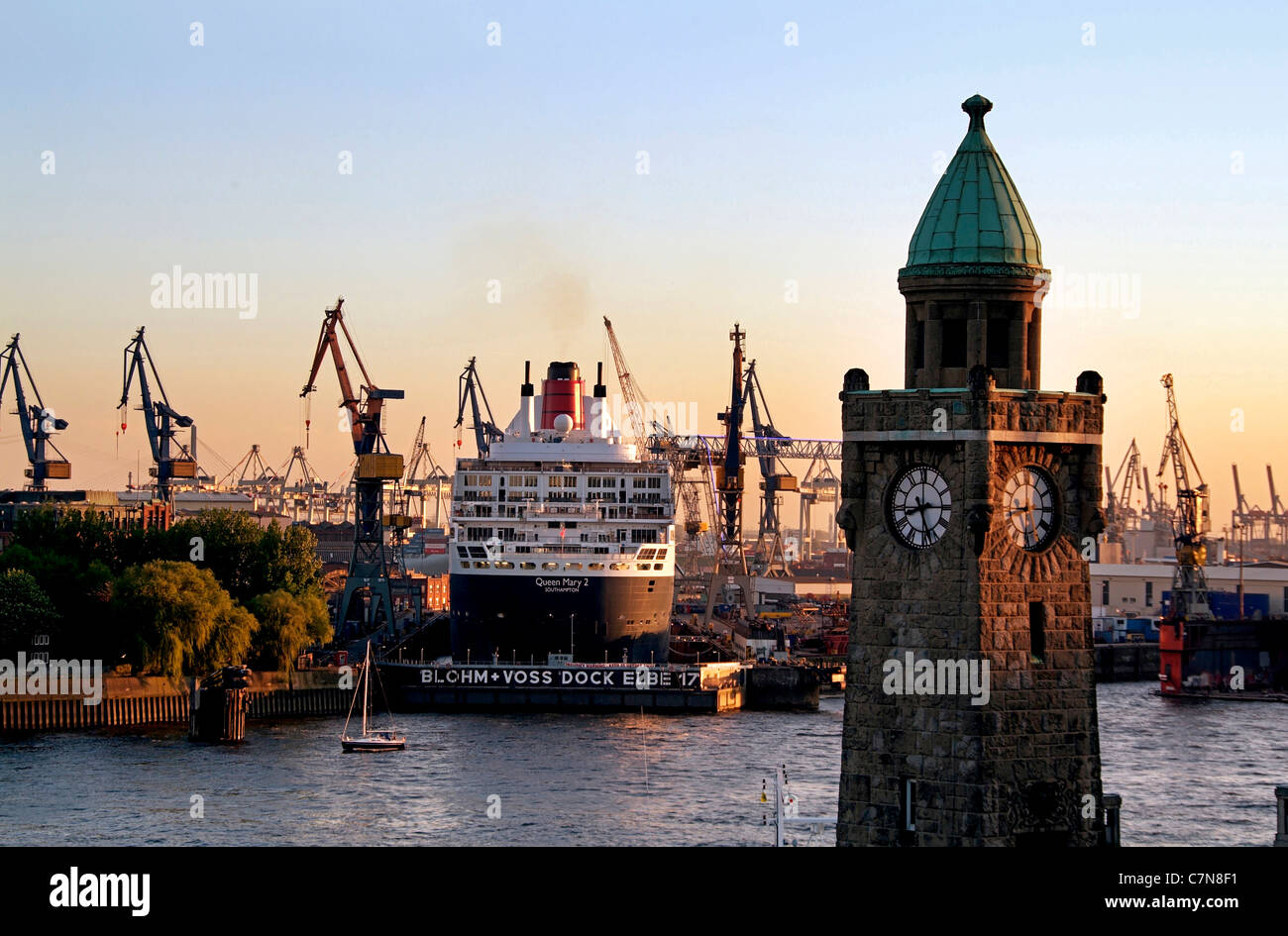 Silhouette of the Landungsbruecken with passenger cruise ship Queen Mary 2 in the shipyards, Hamburg, Germany Stock Photo