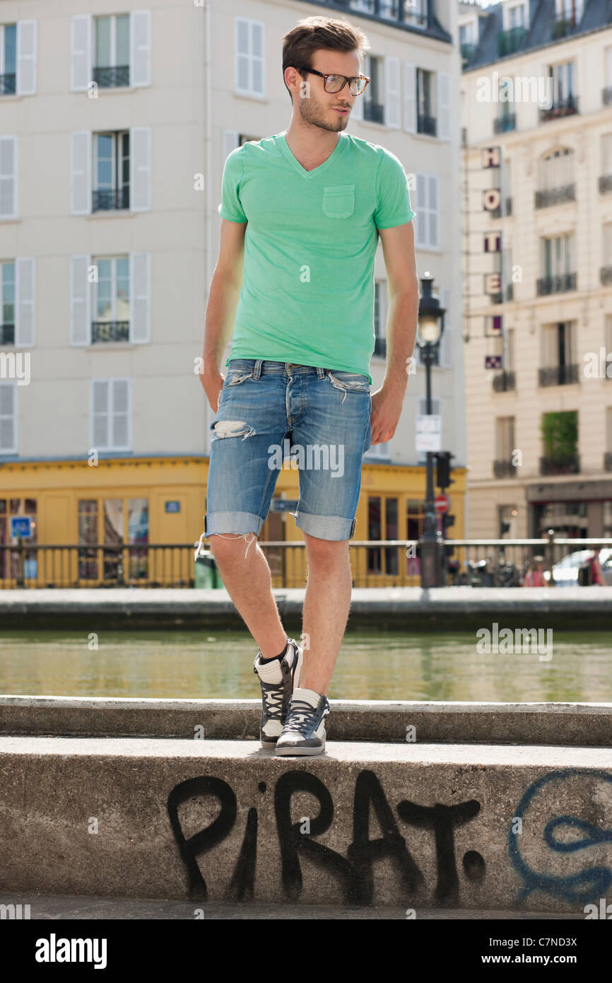 Man standing on the ledge of a canal, Canal St Martin, Paris, Ile-de-France, France Stock Photo