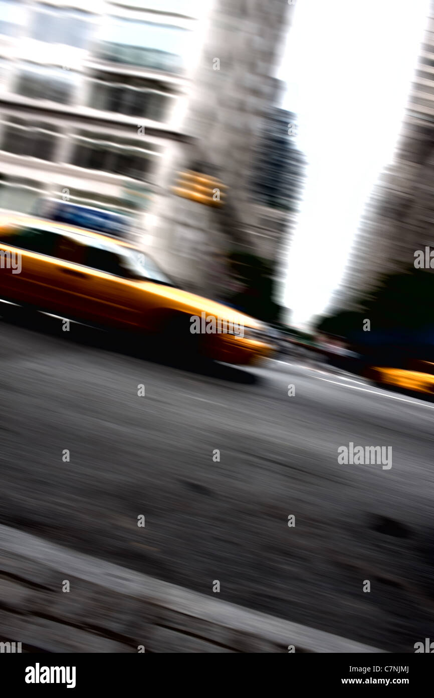 Abstract motion blur of a city street scene at night with a yellow taxi cab speeding by. Stock Photo