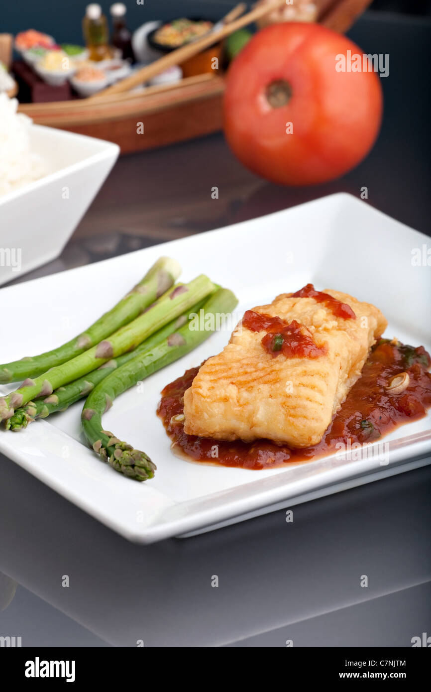 Freshly prepared Thai style sea bass fish dinner with asparagus and appetizer with a contemporary presentation. Stock Photo