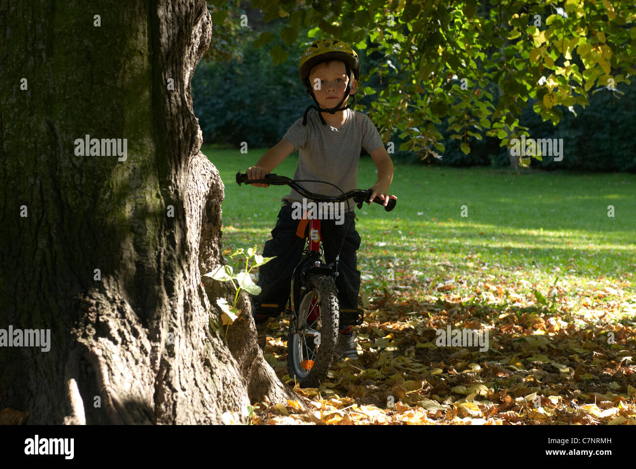 Child blond boy 5 years old riding bicycle with safety helmet in autumn