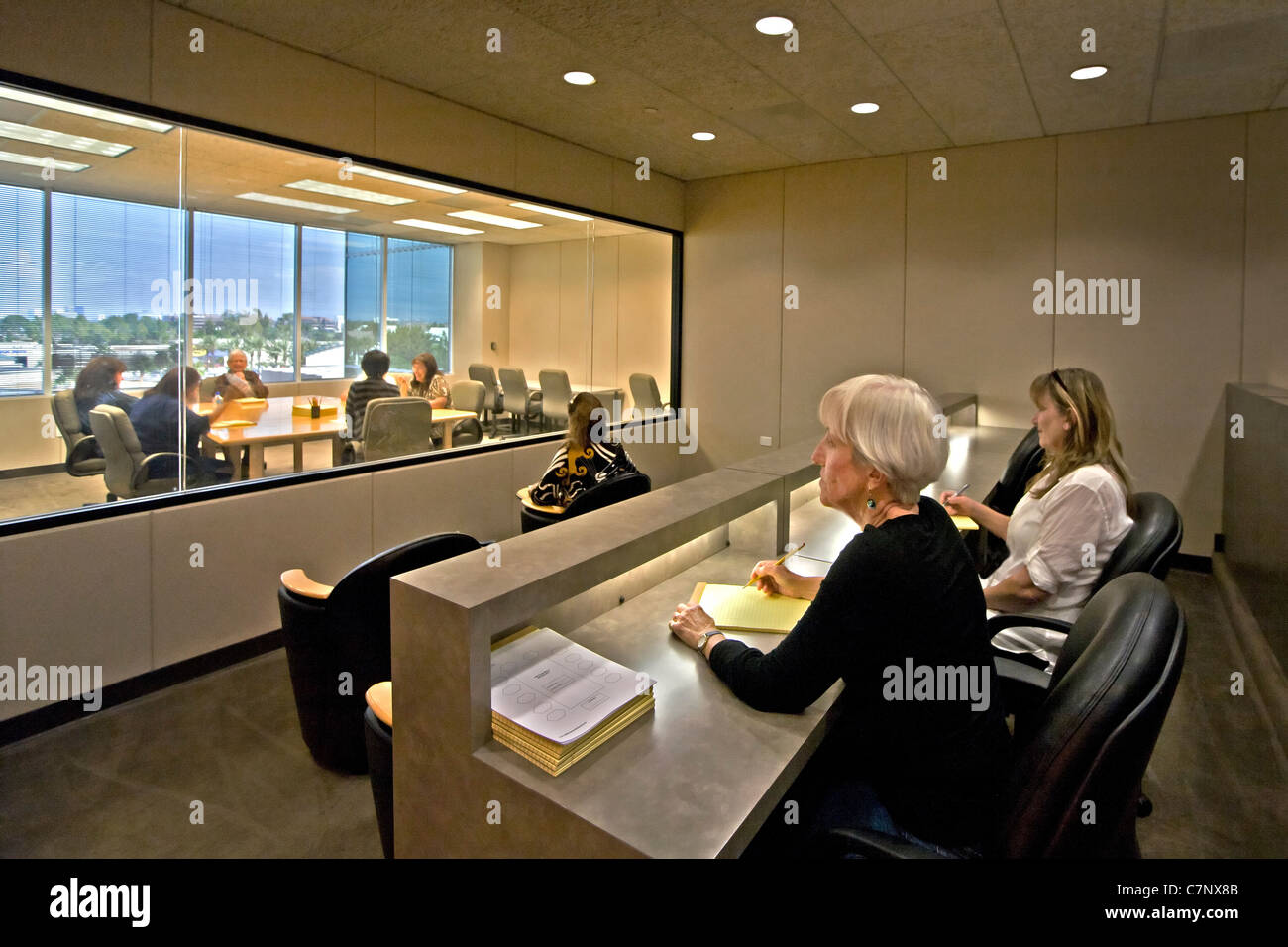 A moderator directs a marketing focus group as clients watch through a one-way mirror at a market research company in Irvine, CA Stock Photo