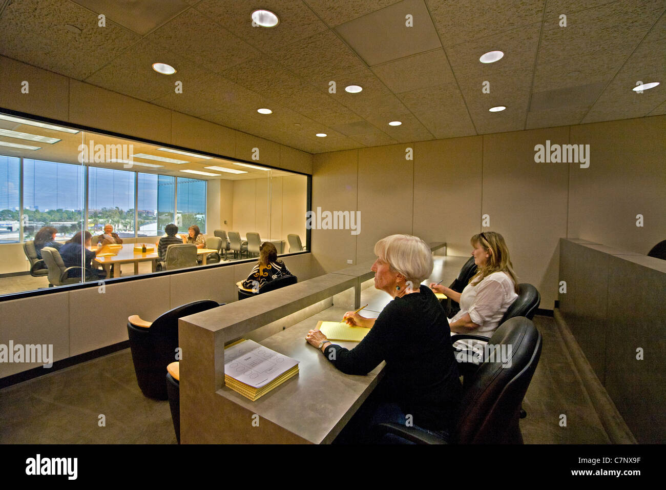 A moderator directs a marketing focus group as clients watch through a one-way mirror at a market research company in Irvine, CA Stock Photo