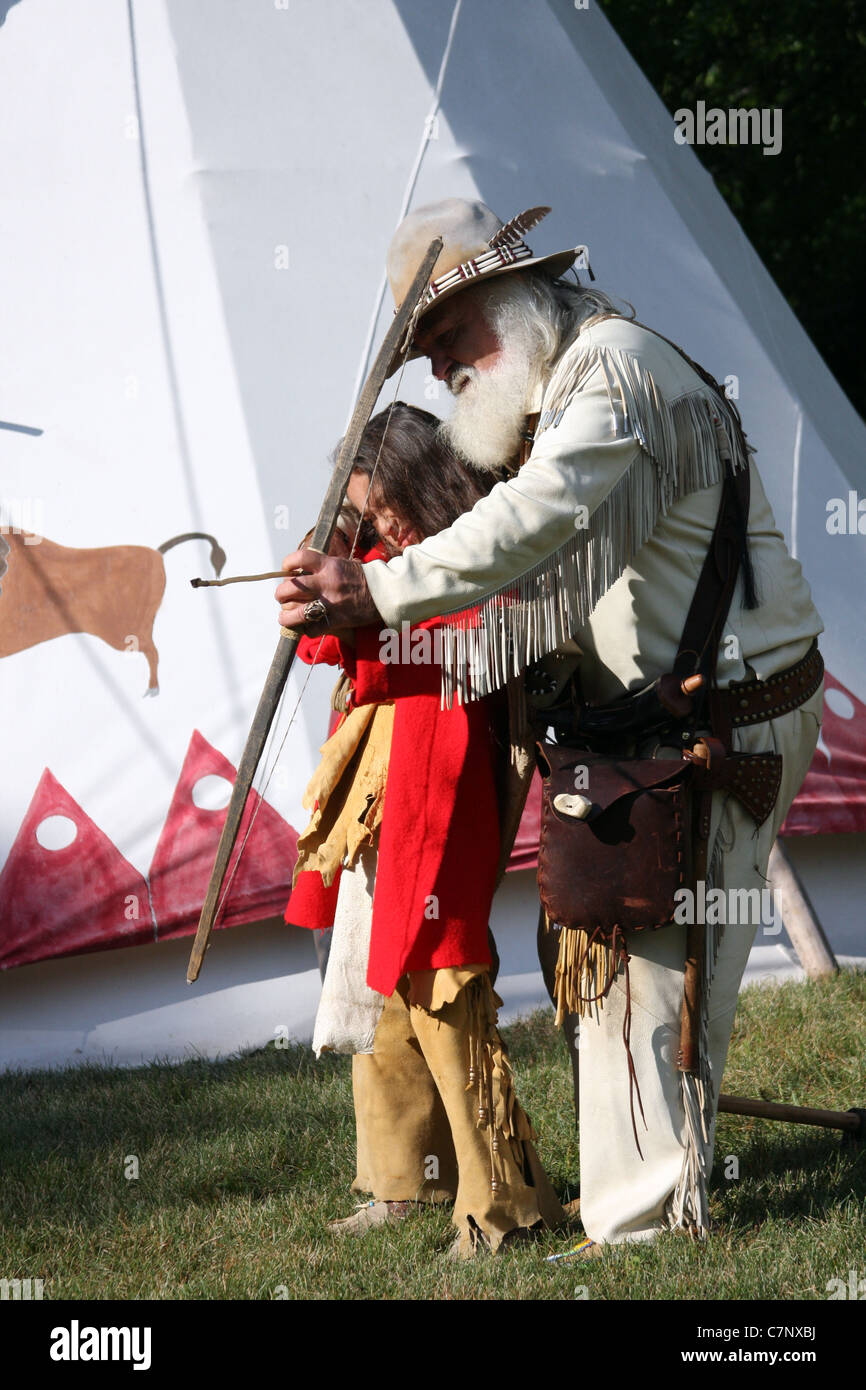 A Native American Indian boy learning how to shoot a bow and arrow ...