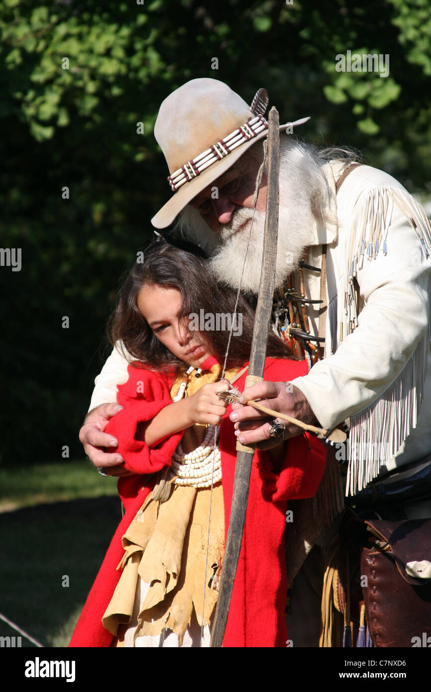 A Native American Indian boy learning how to shoot a bow and arrow ...