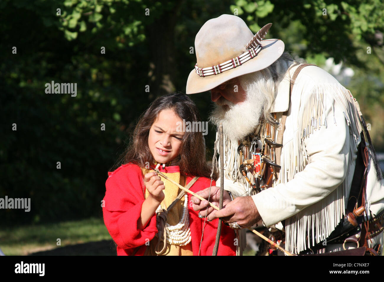 A young Native American Indian boy learning how to shoot a bow and ...