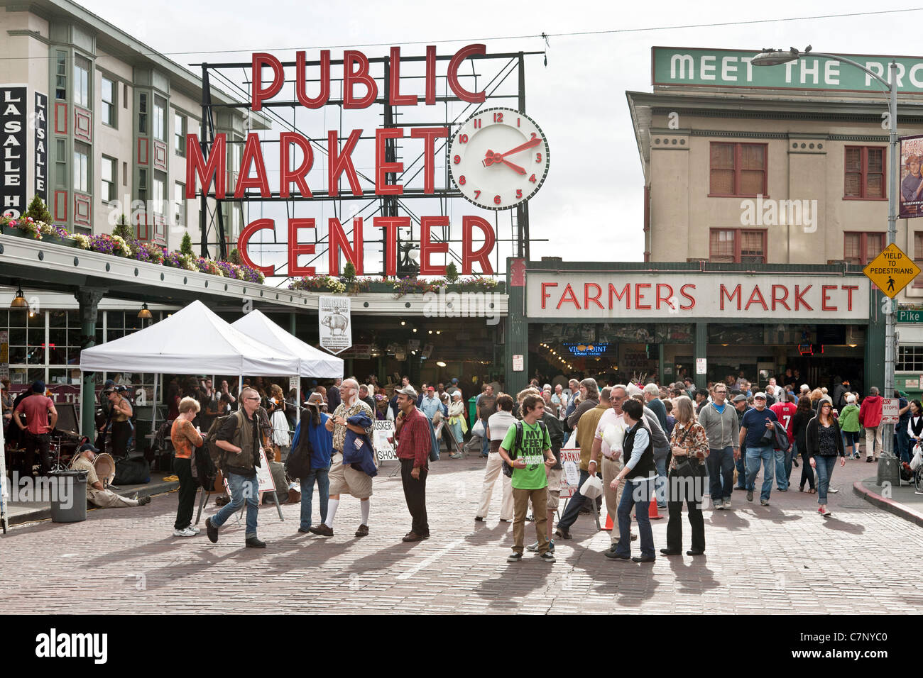 people crowd Pike Place outside main entrance entry to Public Market marked with iconic old vintage retro neon sign Stock Photo