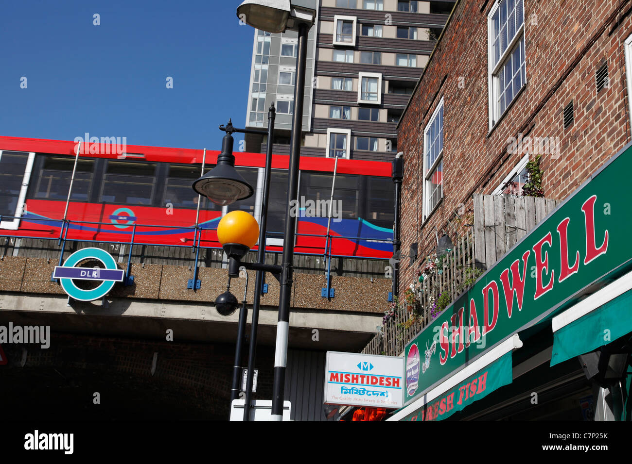 Dockland Light Railway DLR train past Shadwell station in the multi ethnic area of the east end of London, UK Stock Photo