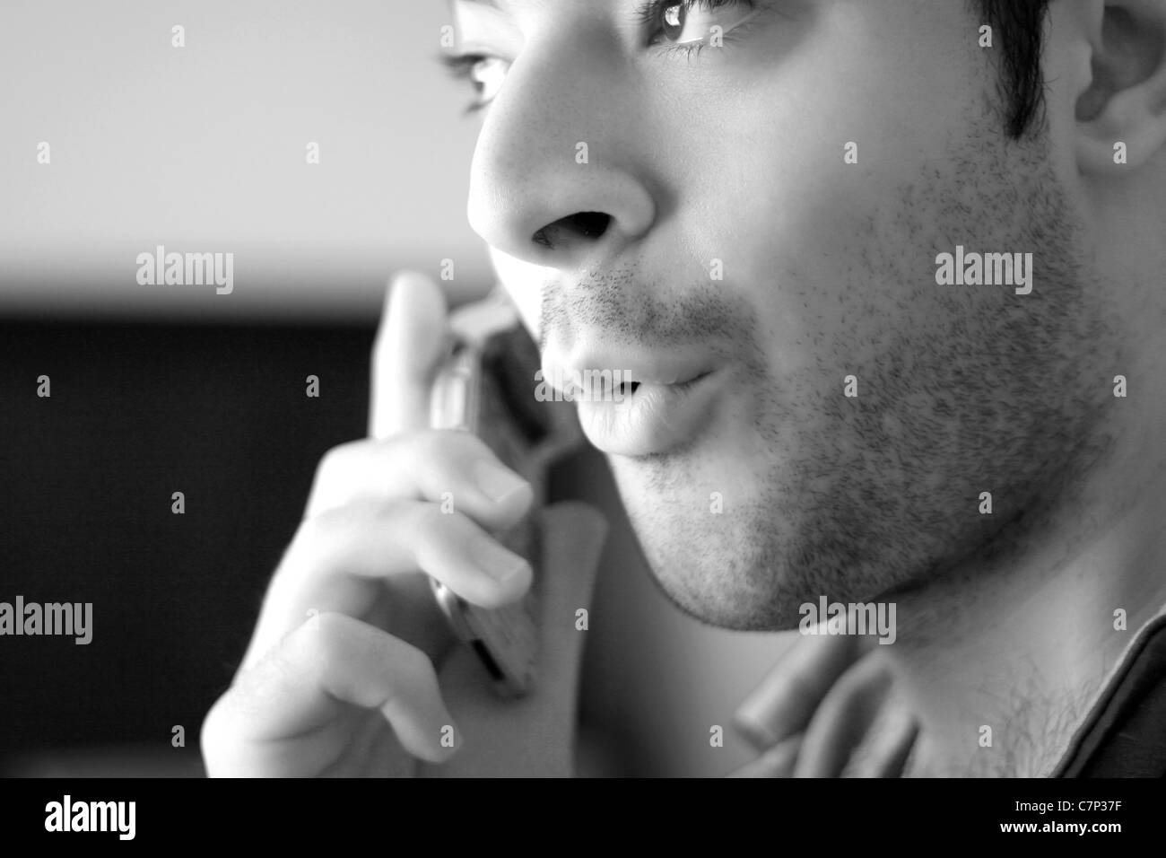 Black and white portrait of a young man on his celly phone - he looks surprised from what he has just heard. Stock Photo