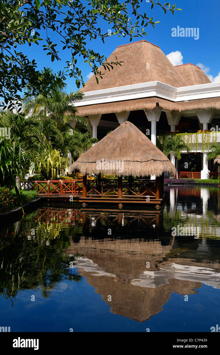 Thatched roof gazebo over pond water at a luxury resort hotel in Mayan Riviera Mexico Stock Photo