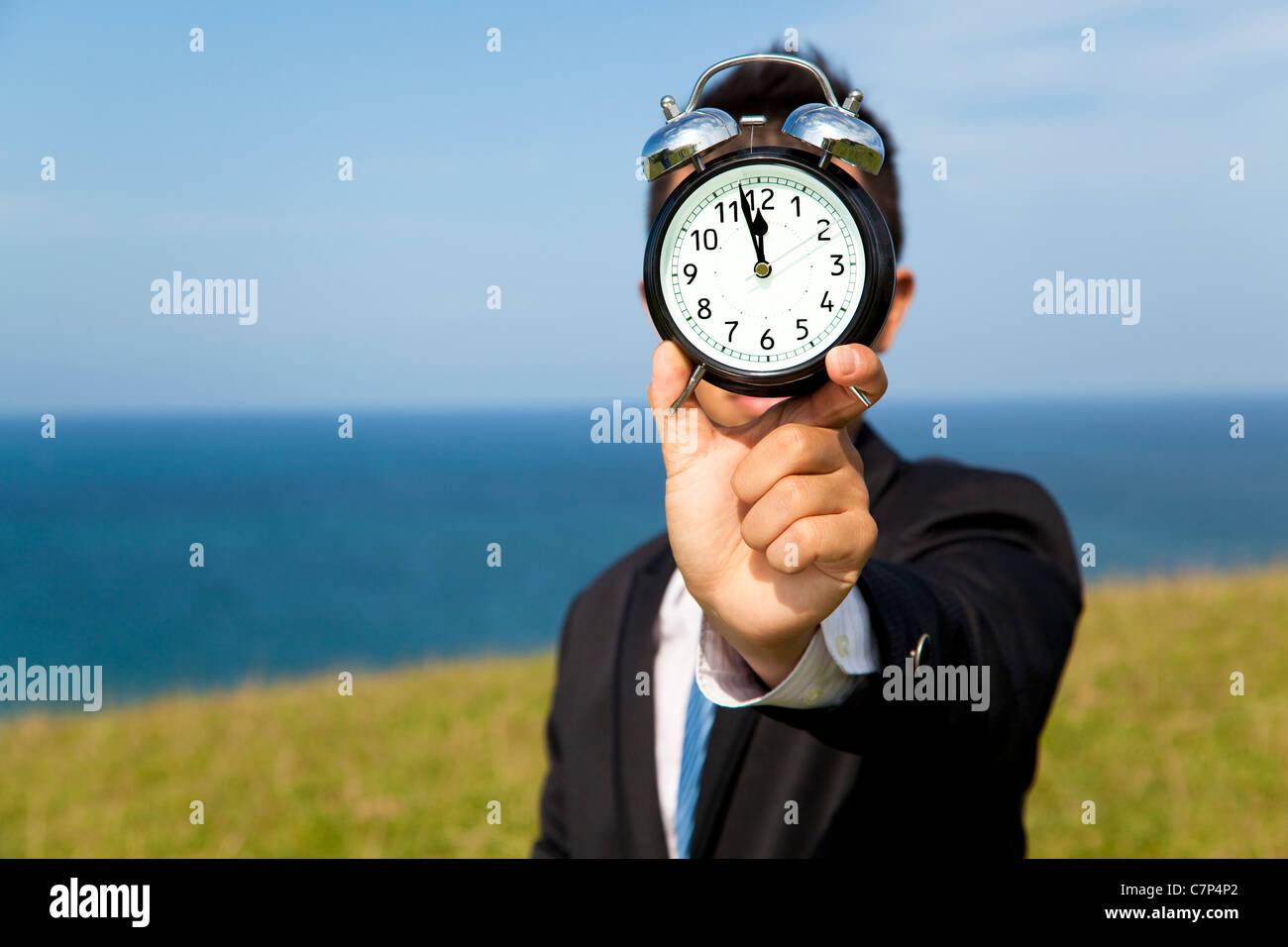 businessman holding clock and standing on the field Stock Photo