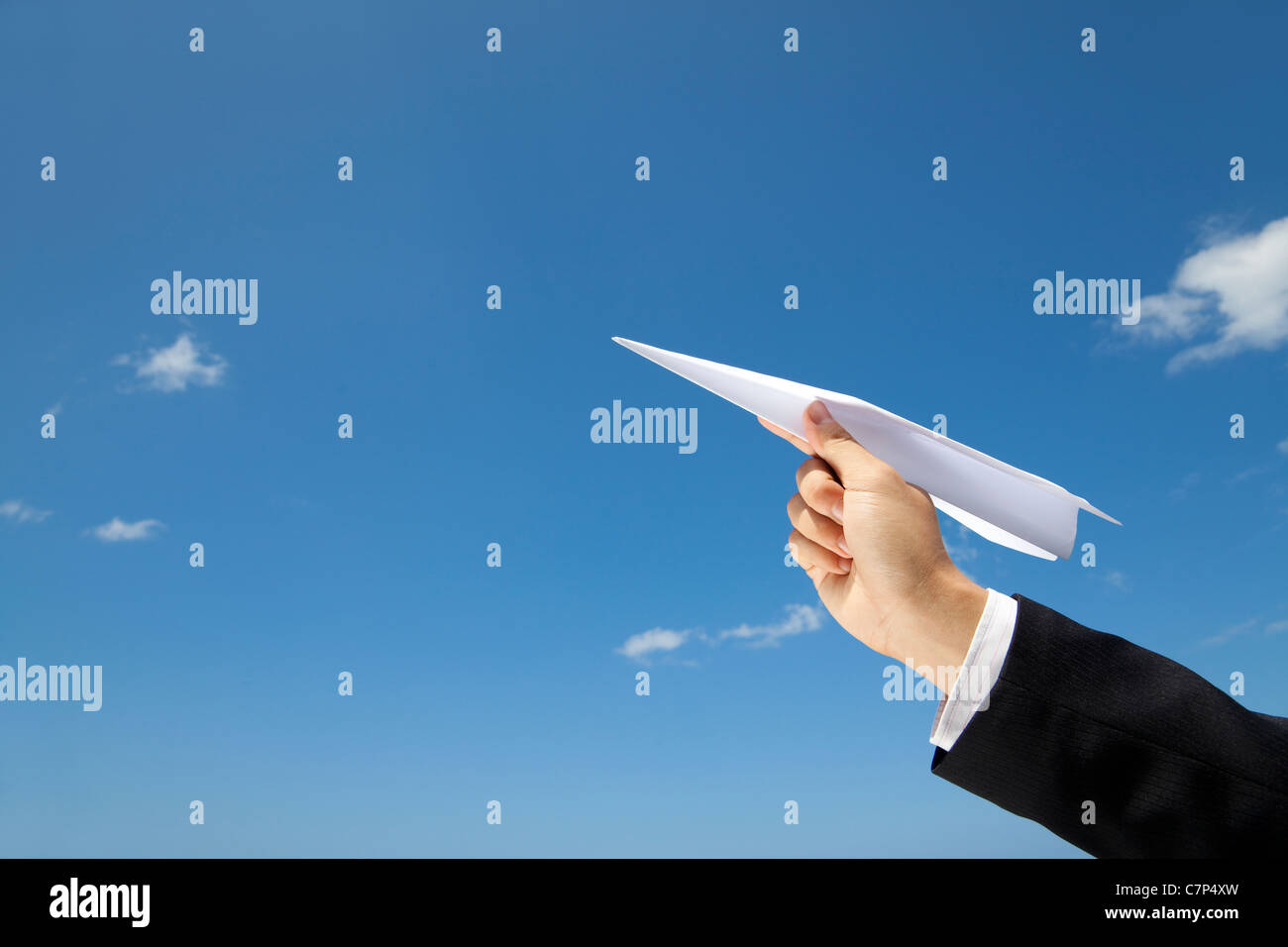 hand of Businessman letting an airplane made of paper fly over blue sky Stock Photo