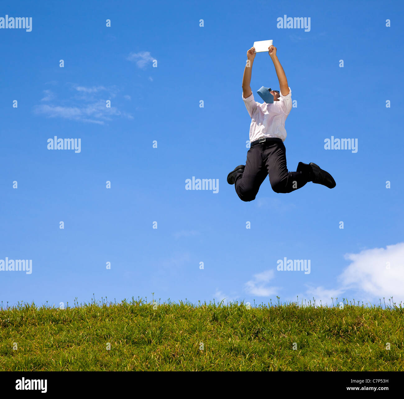 happy businessman holding touch pad and jumping on the hill Stock Photo