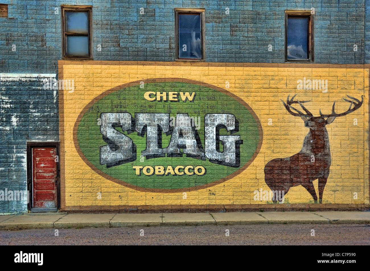 A large antique advertisement for Stag chewing tobacco on the exterior wall of an old abandoned hotel. Stock Photo
