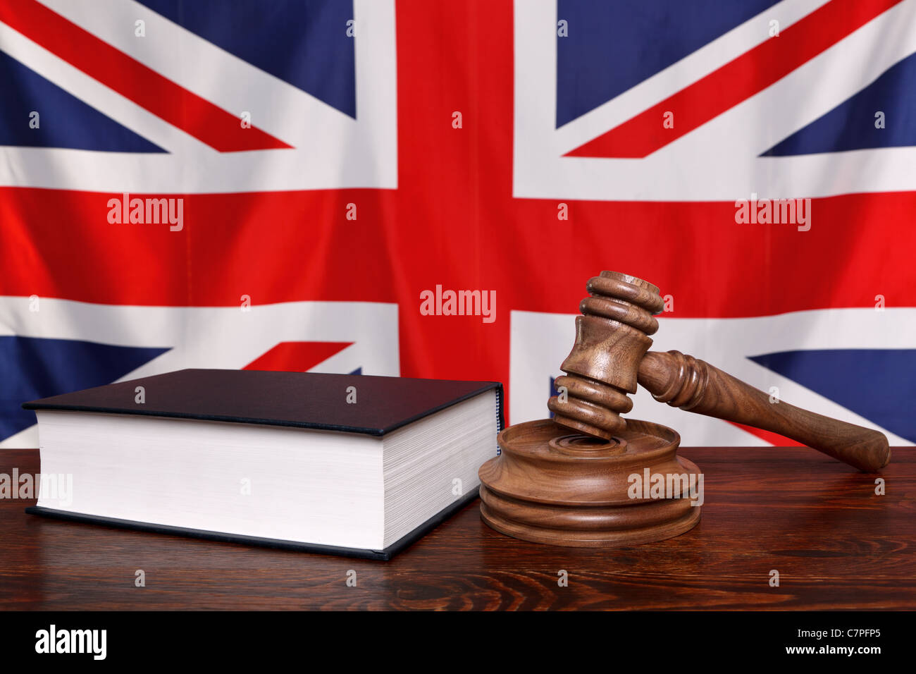 Still life photo of a gavel, block and law book on a judges bench with the United Kingdom union jack flag behind. Stock Photo