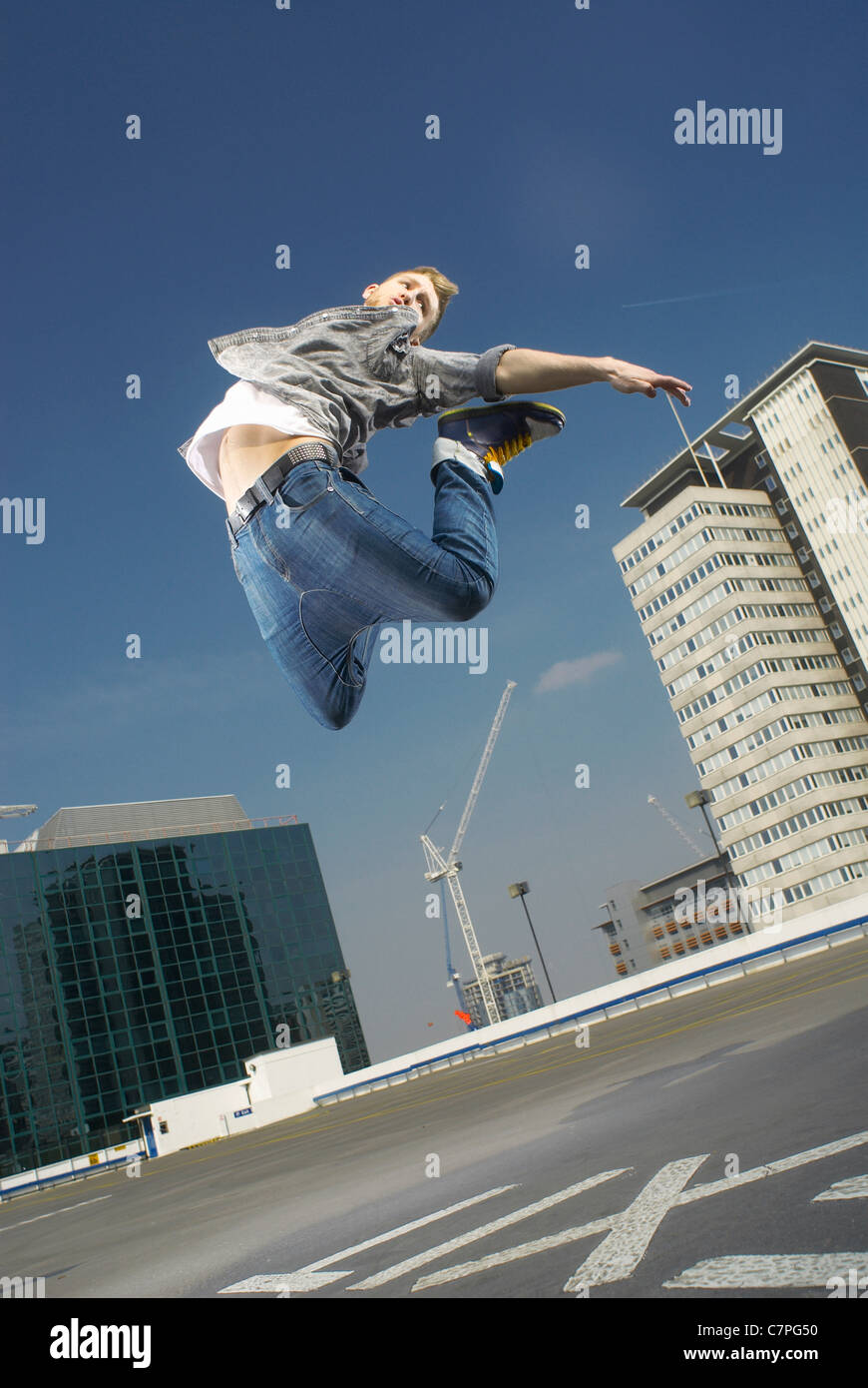 Man jumping on urban rooftop Stock Photo