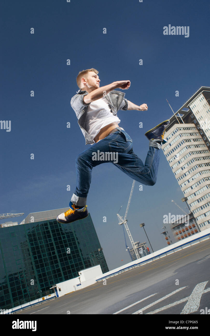 Man jumping on urban rooftop Stock Photo