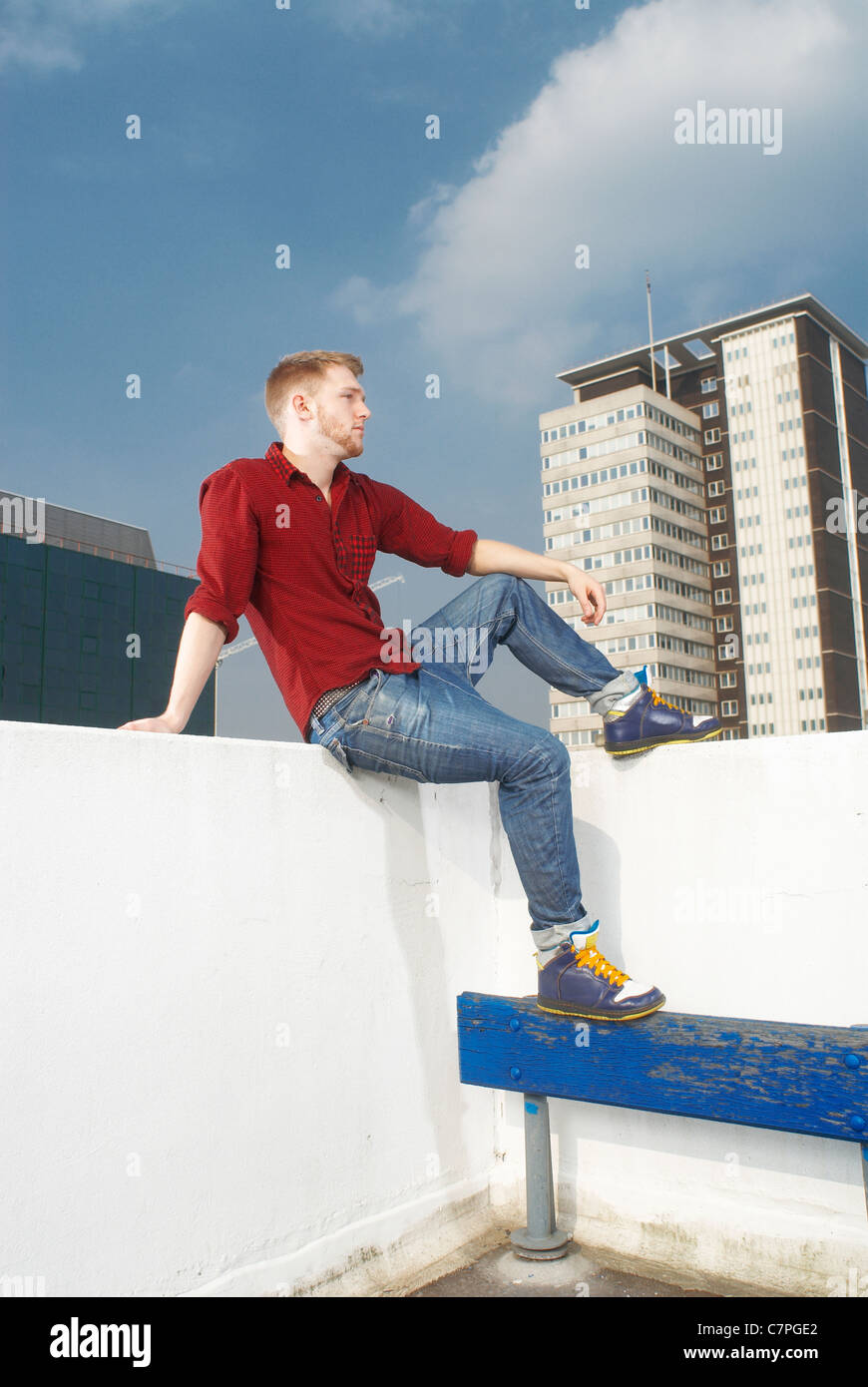 Man sitting on urban rooftop Stock Photo