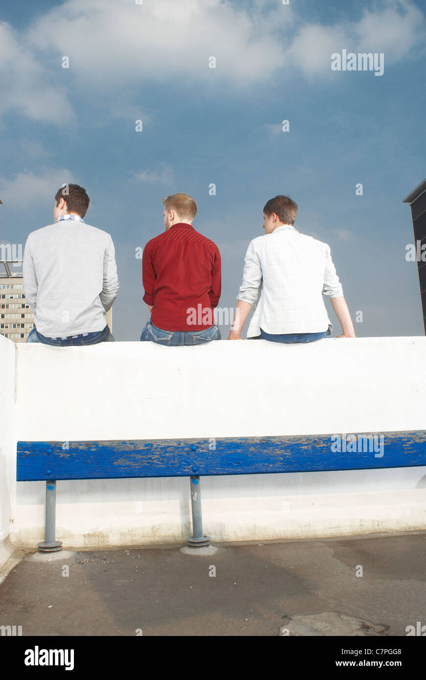 Men sitting on rooftop wall Stock Photo