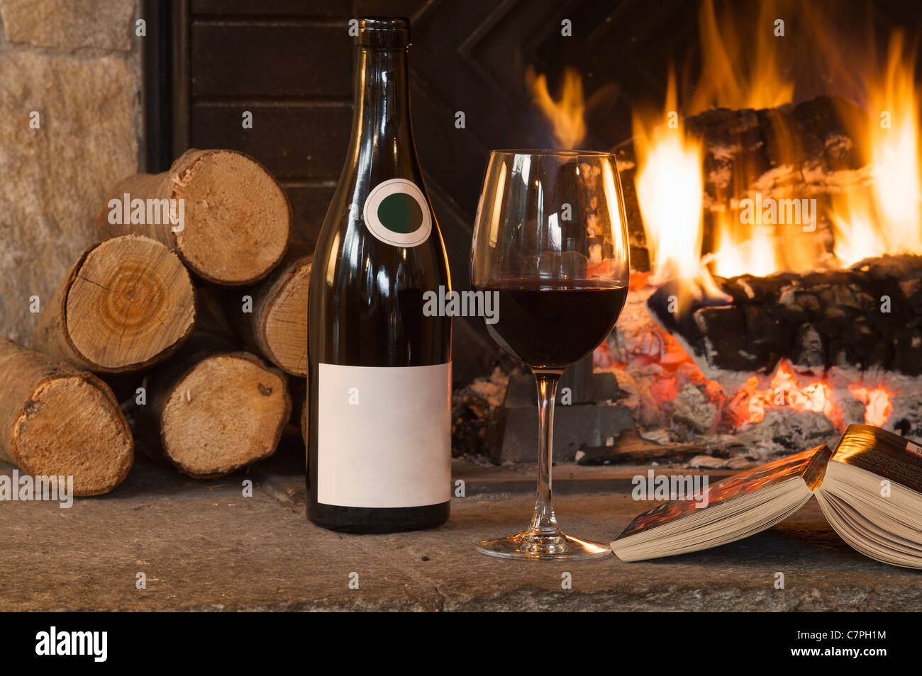 Glass of wine and book by fireplace Stock Photo