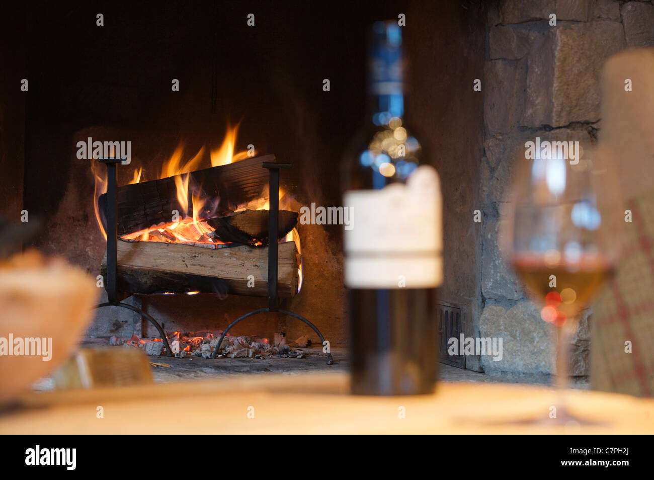 Glass of wine and bottle by fireplace Stock Photo