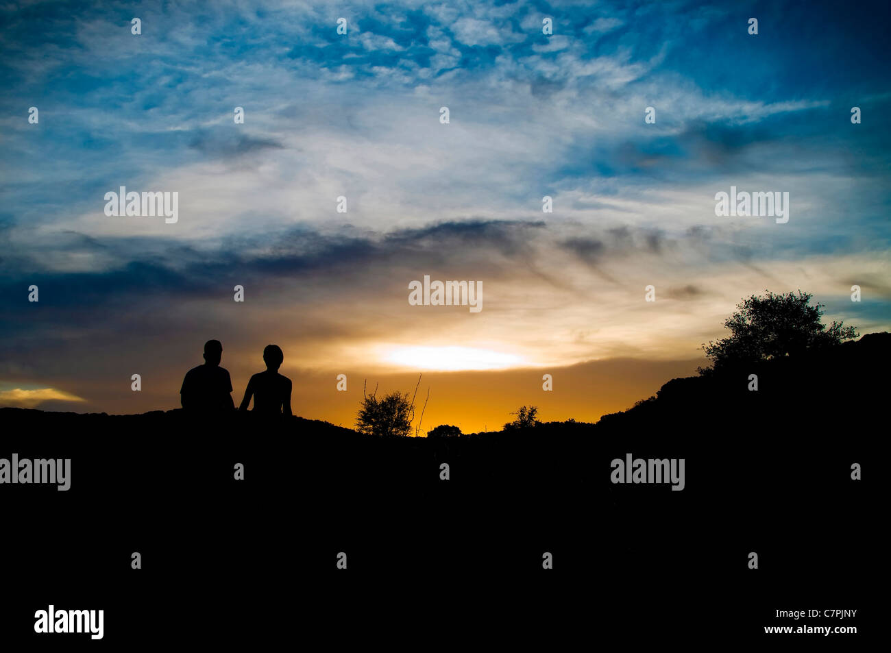 Silhouette of a young couple in love walking into sunset with dramatic ...