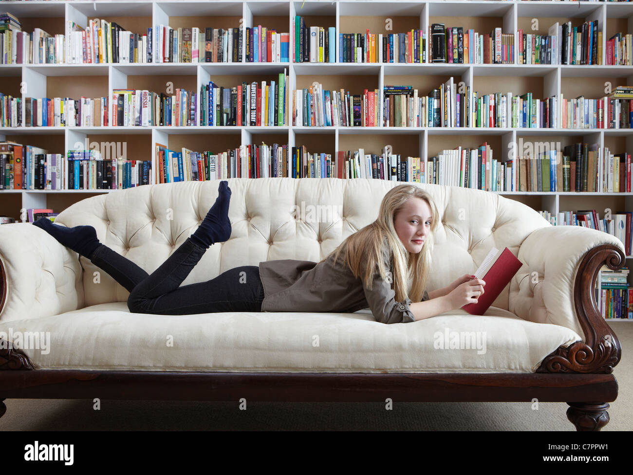 Girl reading on couch in library Stock Photo