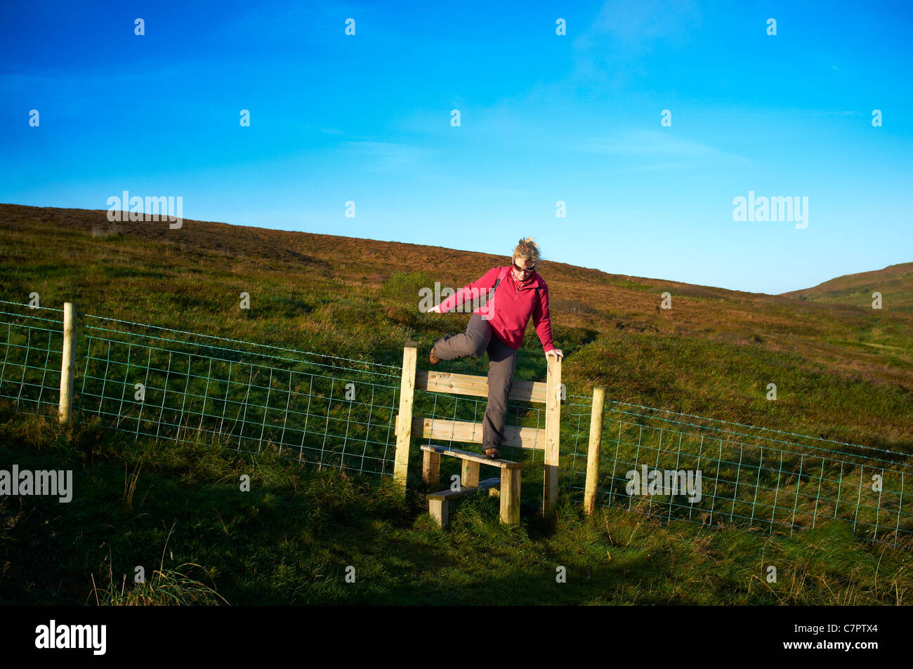 Woman hill walker on Cave Hill climbing over stile Stock Photo