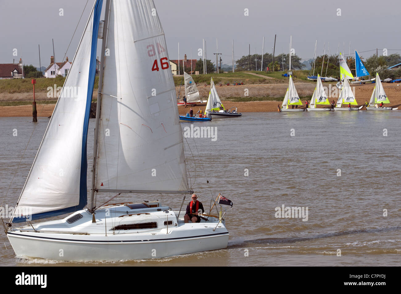 Yacht sailing on the river Deben with Felixstowe Ferry shoreline in