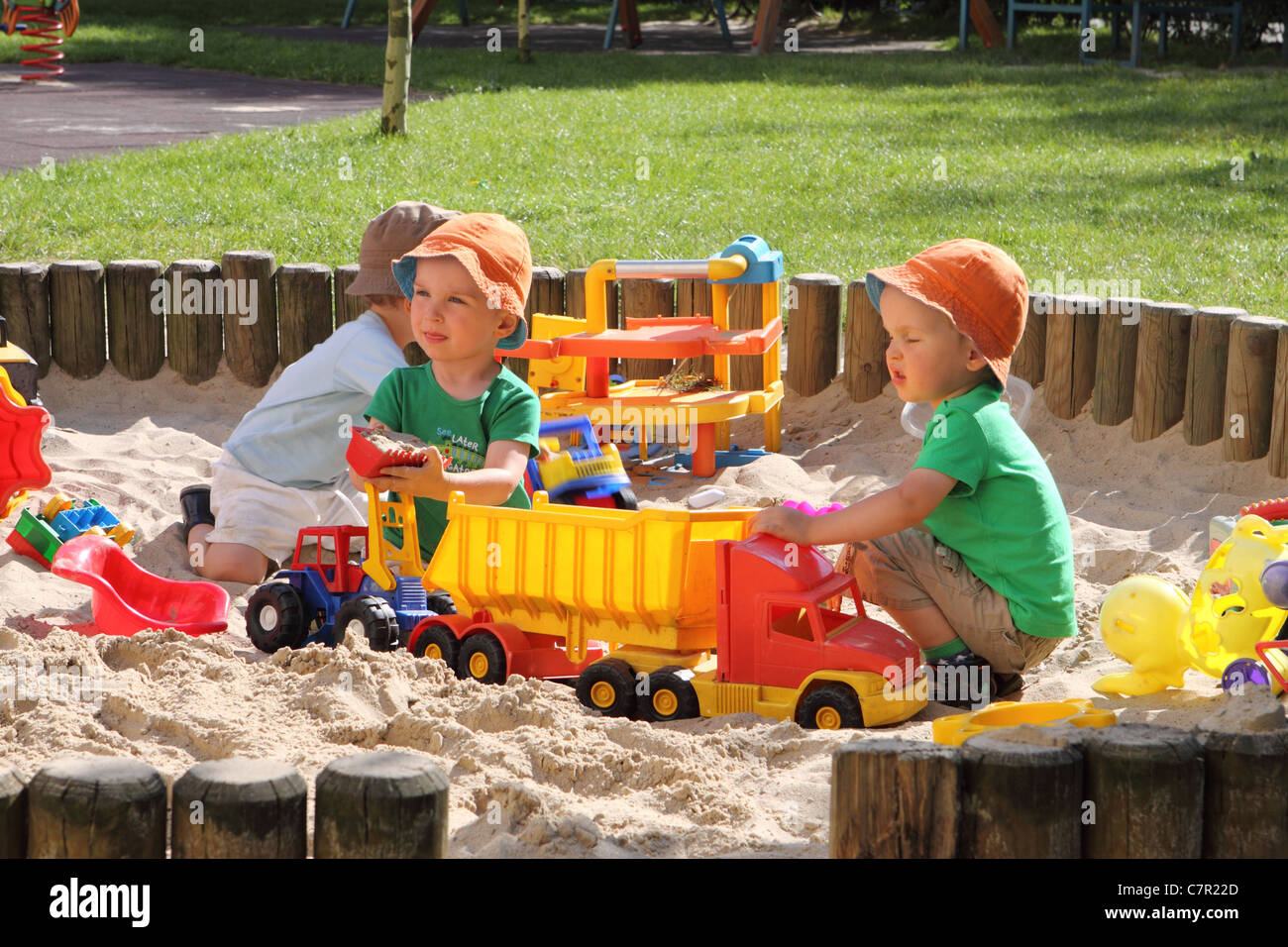 Young children playing in a sandpit with toys Stock Photo