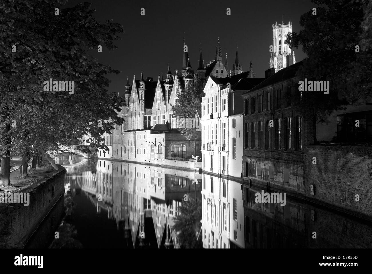 Steenhouwers Canal in Bruges, Belgium with the Belfry and spires of the Stadhuis or Town Hall floodlit at dusk. Color at C7R333 Stock Photo