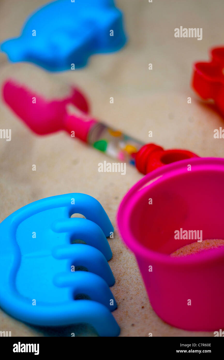 A beach scene with summer sand, bright bucket, spade, rake and other