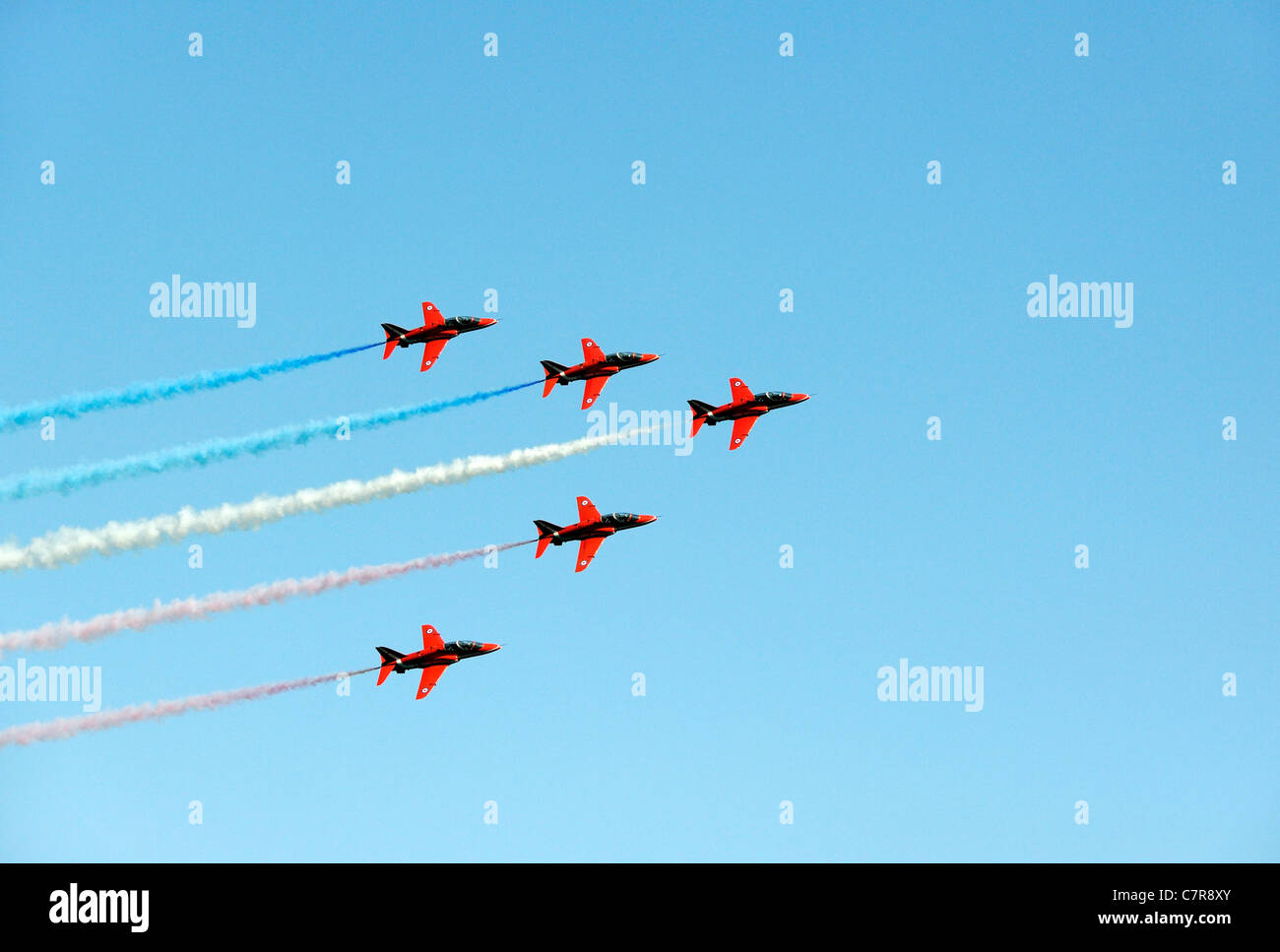 Red Arrows Royal Air Force Aerobatic Team. Formation of five red BAE Hawk T1As trainer aircraft against blue graphic sky Stock Photo