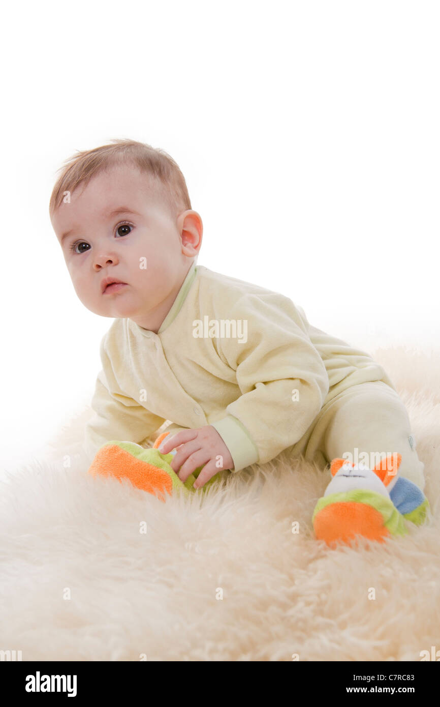 Lovely browneyed baby sits lies on white fur Stock Photo Alamy