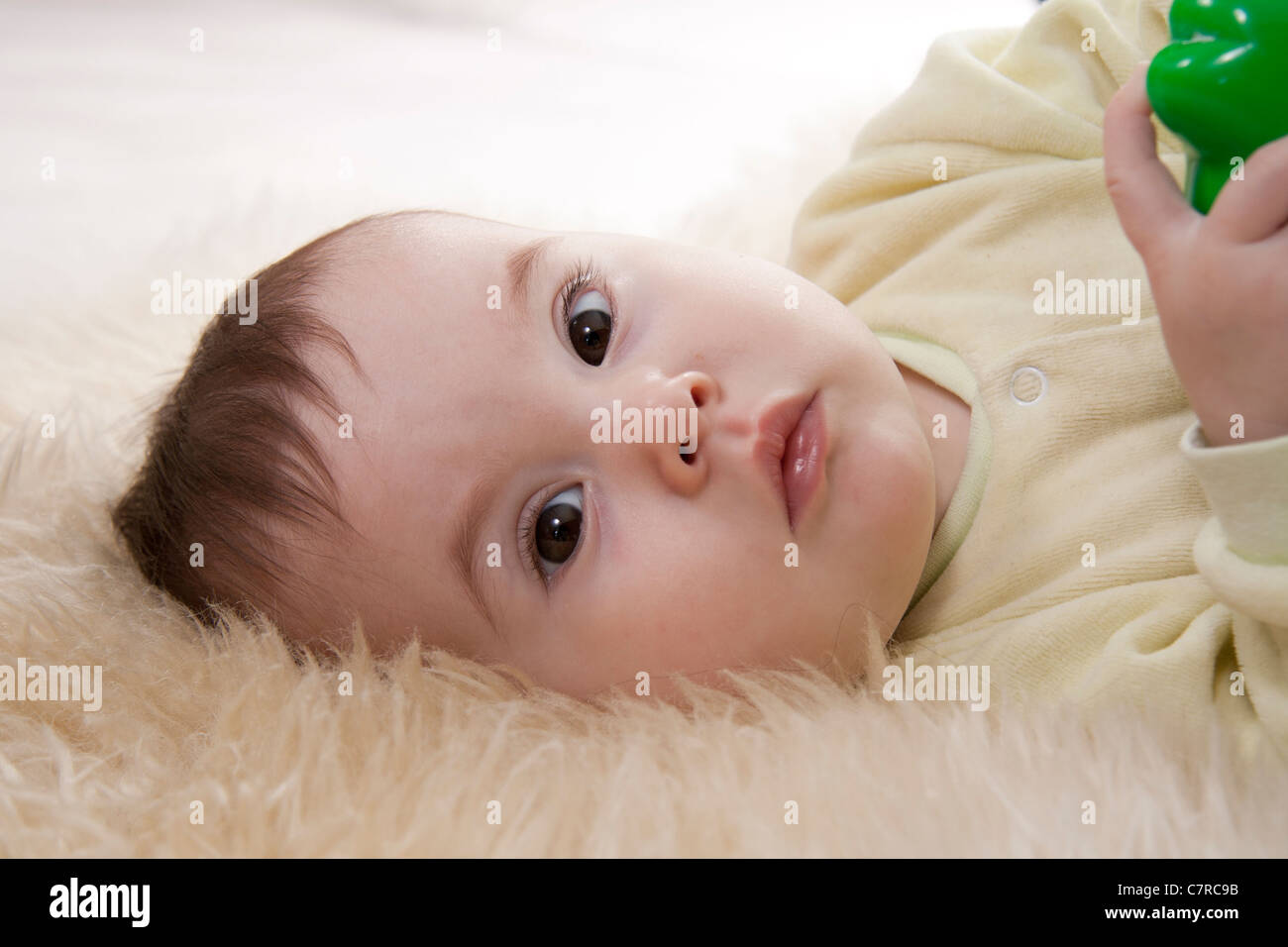 Lovely browneyed baby lies on white fur Stock Photo Alamy
