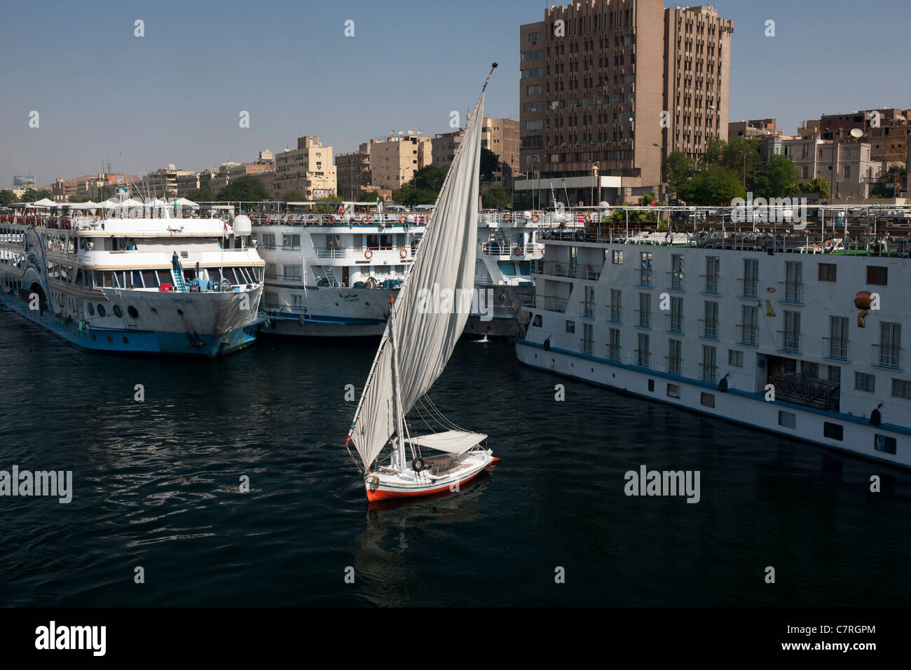 Falucca sails on the River Nile at Aswan, Egypt, Africa, with cruise boats moored alongside. Stock Photo