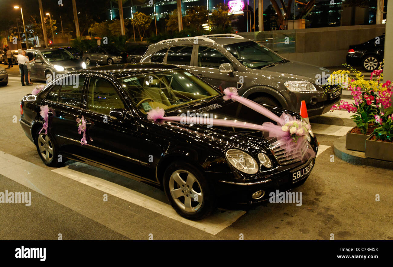 Black wedding limousine with pink ribbons, reflecting rows of hotel