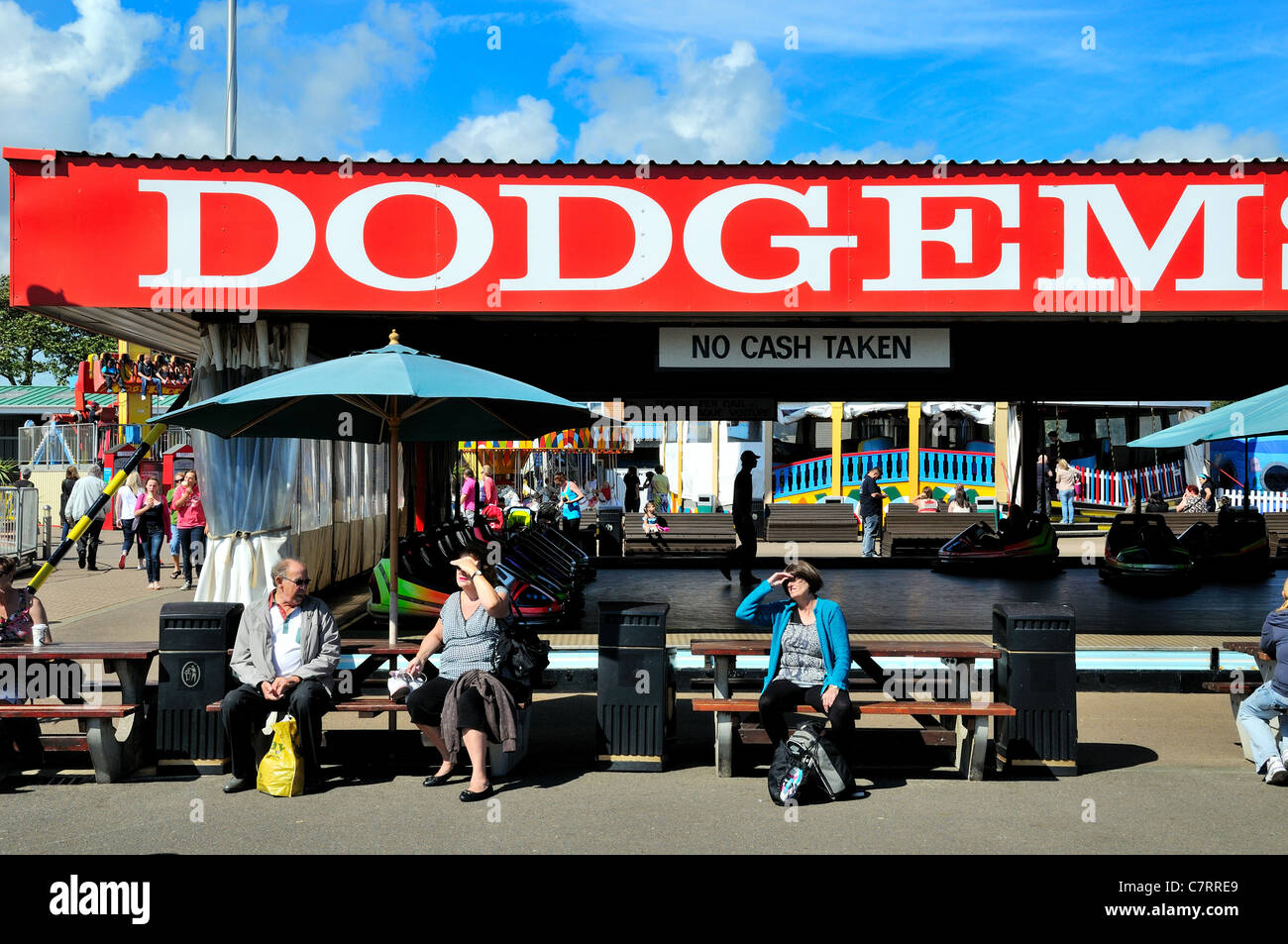 People sitting in front of a dodgem fairground ride on the seafront at Littlehampton Sussex England UK Stock Photo
