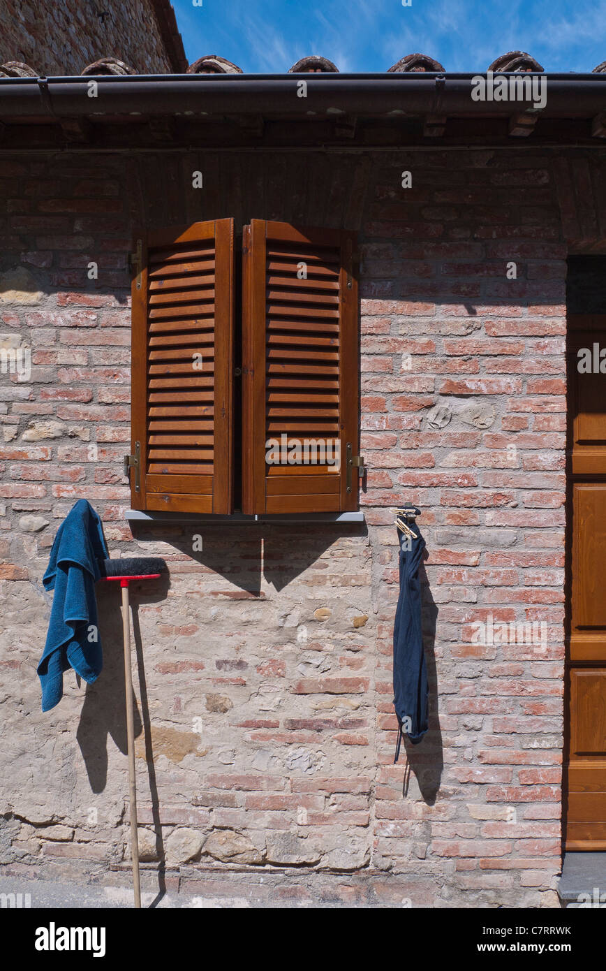Cleaning rags and a sponge mop are hung to dry against the side of a brick building in Citta