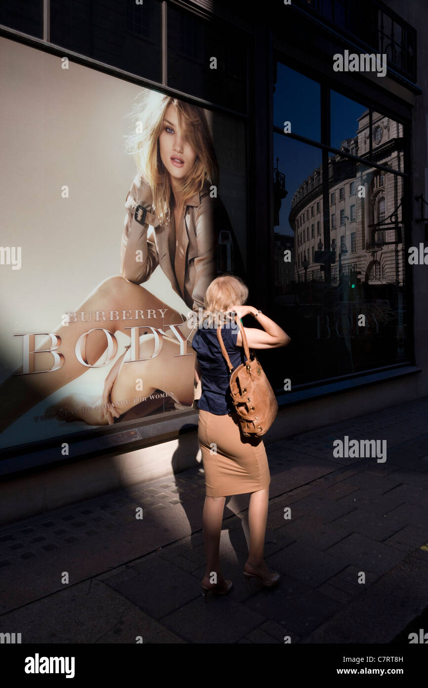 Woman walks past a giant Burberry poster girl in central London. Stock Photo