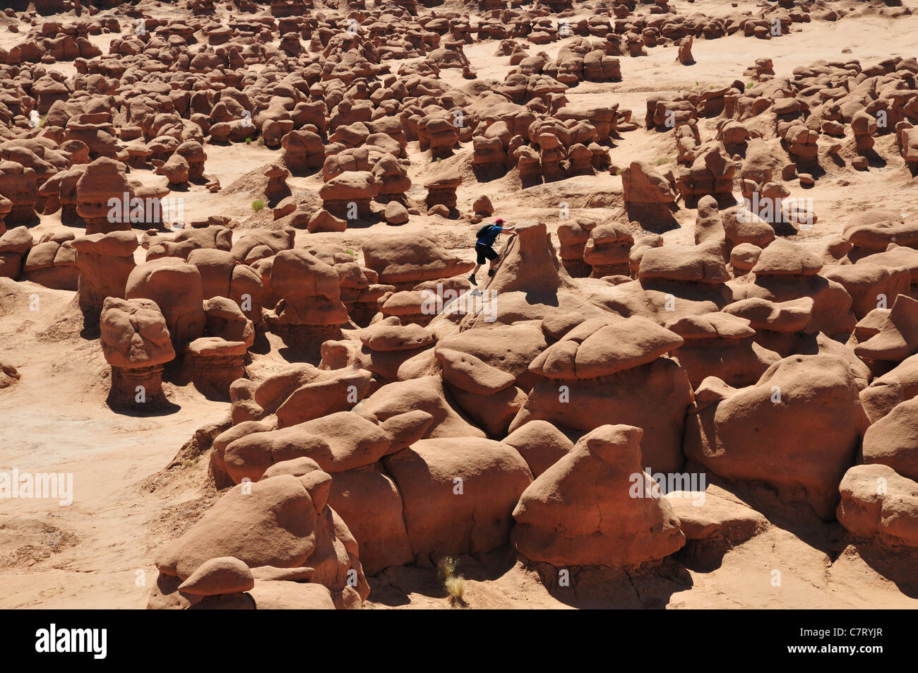A young man climbs one of the rock formations in Goblin Valley State Park, Utah Stock Photo
