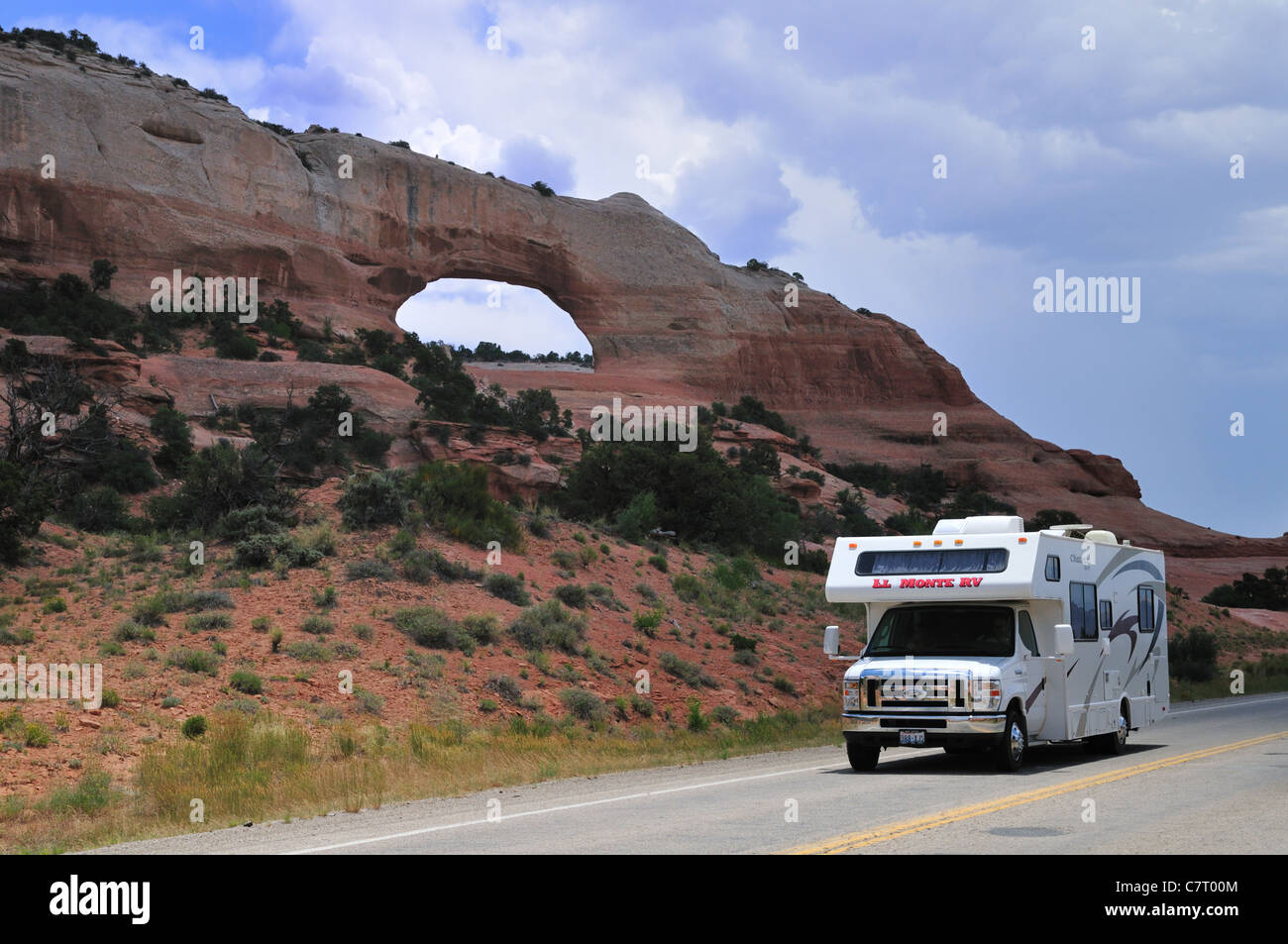 A motorhome camper glides by the Wilson arch, Monticello, Utah Stock