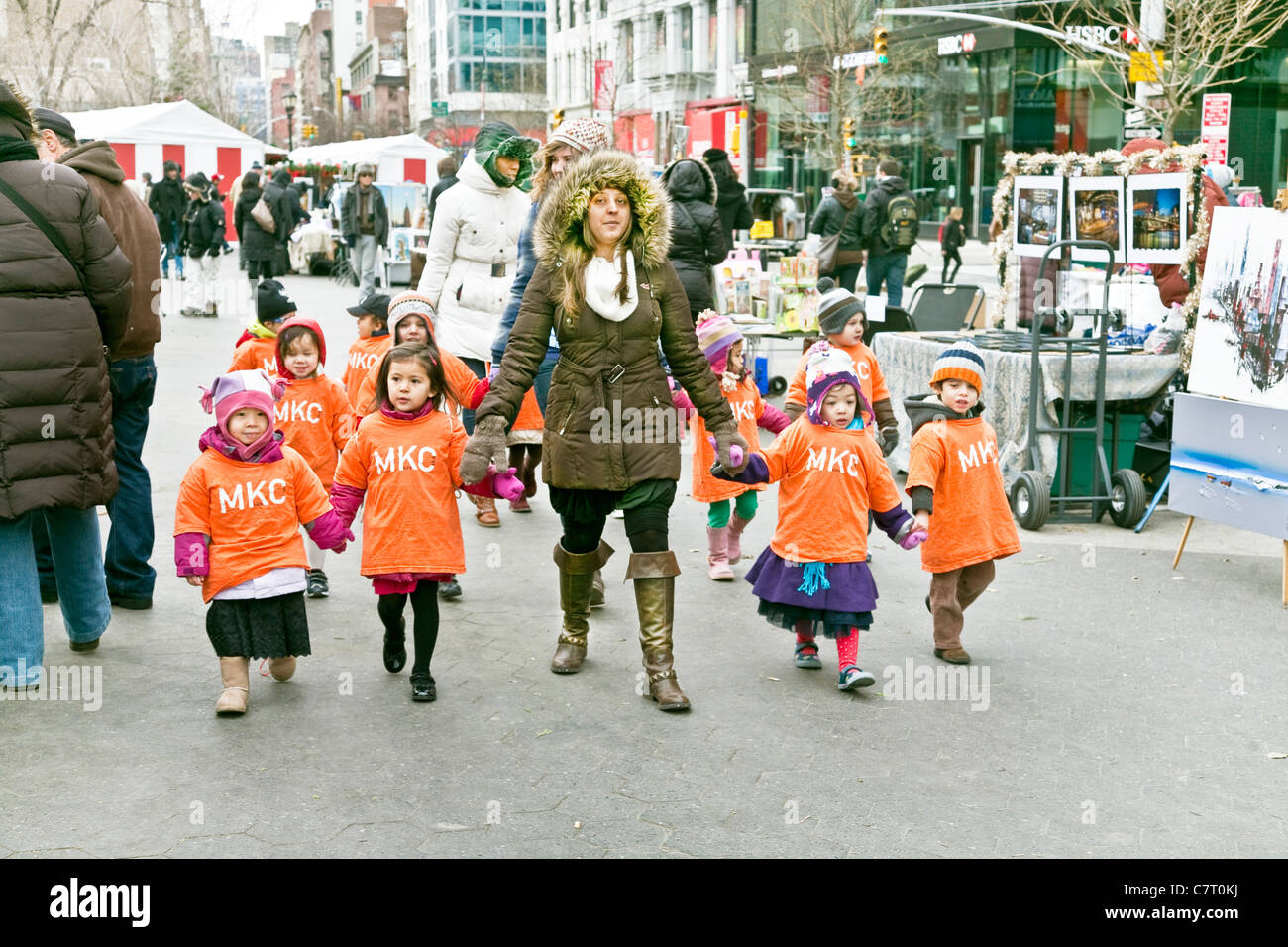 group of preschool daycare boys & girls wearing identical orange jerseys with teachers enjoy Christmas outing to Union Square Stock Photo