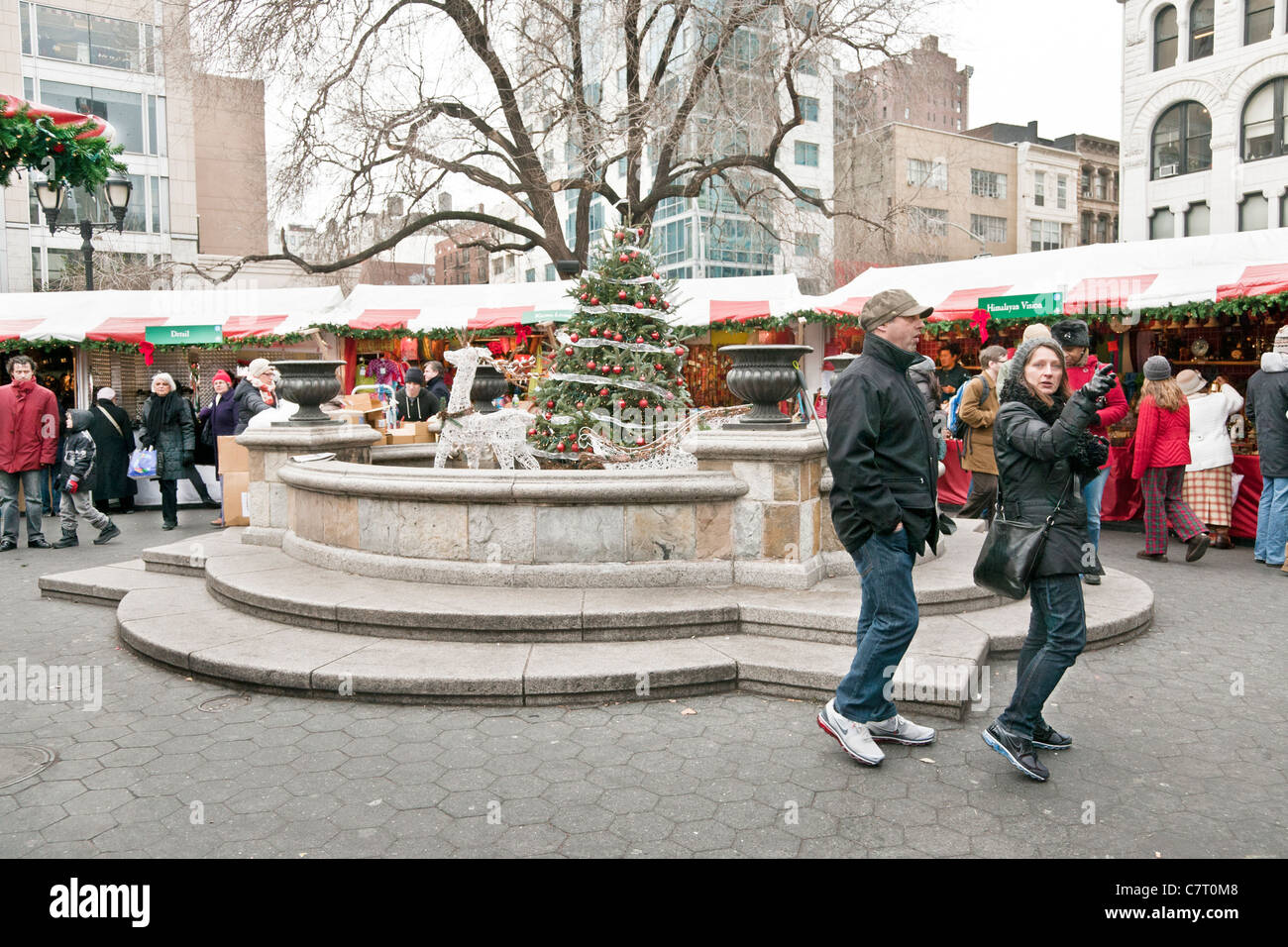 Christmas market kiosks shoppers surround Union Square fountain decorated with tree & white wire openwork reindeer & sleigh Stock Photo