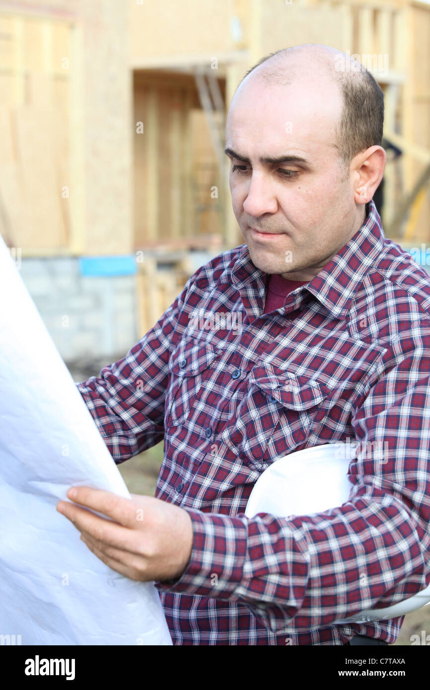 Housebuilder looking at plans on site Stock Photo - Alamy