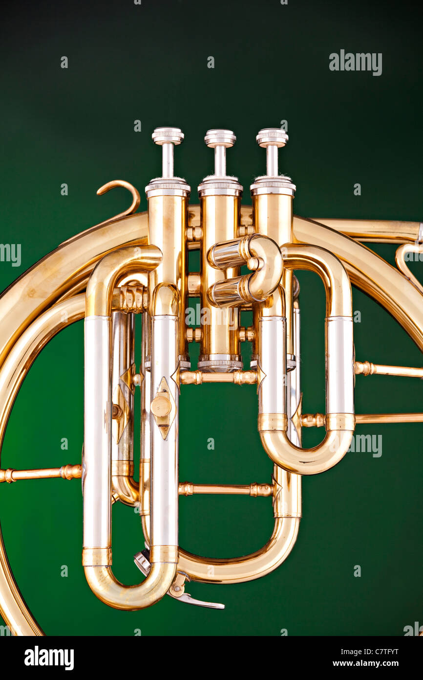 An antique French horn or peckhorn isolated against a spotlight green